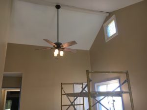 Ceiling fan spinning in a room with a window, allowing natural light to illuminate the space.