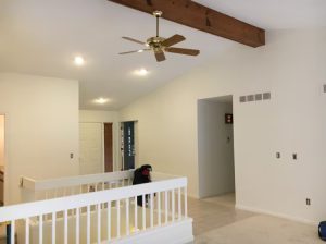 A cozy room featuring a ceiling fan and a staircase, creating a welcoming and airy atmosphere.