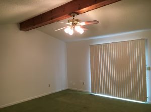 Empty room featuring a ceiling fan and a sliding door, creating a spacious and airy atmosphere.