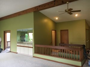 A room featuring green walls and a ceiling fan, creating a vibrant and refreshing atmosphere.