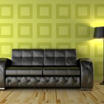 A green wall features a sleek black sofa beside a modern lamp, creating a stylish and inviting living space.